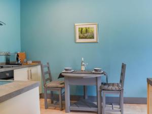 a table and chairs in a kitchen with a blue wall at Ty Ffair Mai Annexe in Llangwm-isaf