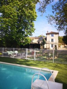 una piscina frente a una valla con una casa en LE REPAIRE gîte 4 étoiles, en Chasseneuil-du-Poitou