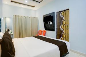 バラナシにあるSuper OYO Flagship SHIVA VALLEY HOTELのベッドルーム1室(ベッド1台、壁掛けテレビ付)