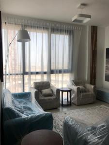 a living room with two couches and a large window at أجمل مكان in Al Ḩamrīyah
