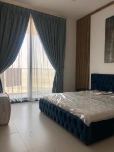 a bedroom with a bed and a large window at أجمل مكان in Al Ḩamrīyah
