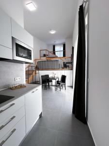 eine Küche mit weißen Schränken und einem Tisch mit Stühlen in der Unterkunft Grazora Living Apartments in Graz