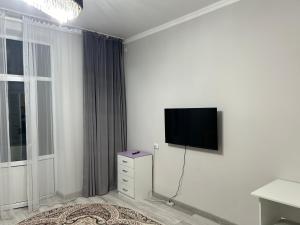 Dieses weiße Zimmer verfügt über einen Flachbild-TV an der Wand. in der Unterkunft GuKu Fly Apart in Turksib