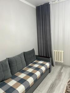 ein Wohnzimmer mit einer Couch mit einer karierten Decke in der Unterkunft GuKu Fly Apart in Turksib