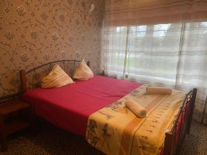 una camera da letto con un letto con lenzuola rosse e una finestra di Park Hotel Kekava a Ķekava
