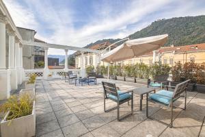 een patio met stoelen, een tafel en een parasol bij (5 bedrooms) 3 Seasons Villa on Como Lake in Como