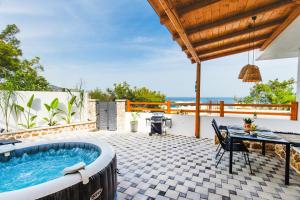 a patio with a hot tub and a table at Casa Zoe Luxurious Retreat in Archangelos