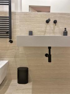 a bathroom with a white sink and a black trash can at Veneto Serviced Apartment by SupaStays in Rome