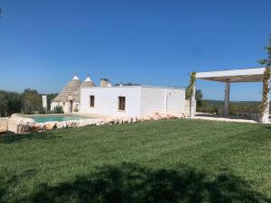 Biały dom z ogródkiem i basenem w obiekcie Trullo Perla Greta - Luxury Country Villa & private heated pool w Alberobello