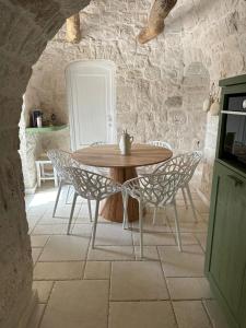 stół i krzesła w pokoju z kamienną ścianą w obiekcie Trullo Perla Greta - Luxury Country Villa & private heated pool w Alberobello