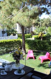 een tafel met een vaas met bloemen en roze stoelen bij Vala Mar Apartament in Durrës