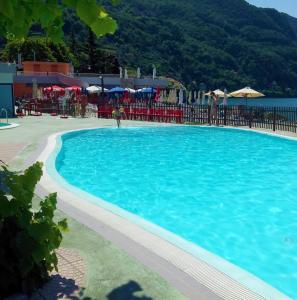 ein großer blauer Pool mit Stühlen und Sonnenschirmen in der Unterkunft La Mimosa di Bellano in Bellano
