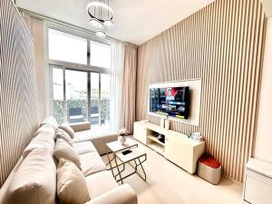 a living room with a white couch and a tv at Amazing 1Bedroom Plus Maid in Avencia at Damac Hills 2 in Dubai