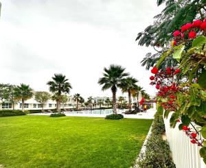 a park with green grass and palm trees and red flowers at Amazing 1Bedroom Plus Maid in Avencia at Damac Hills 2 in Dubai