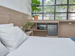 a bedroom with a white bed and a tv at Stanza Hotel Medellin in Medellín