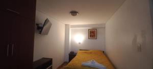 Habitación pequeña con cama con manta amarilla en HOTEL F0NTEs GLOBAL, en Tacna