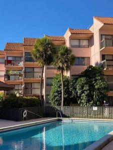 - une piscine en face d'un bâtiment avec des palmiers dans l'établissement Presidential Golfview Condominiums, à West Palm Beach