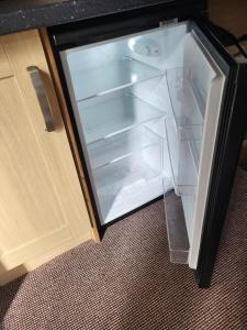 an empty refrigerator with its door open next to a cabinet at Station Guesthouse in Lancaster