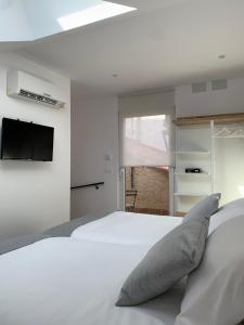 a bedroom with a white bed and a flat screen tv at Apartamentos Lux Carrión in Carrión de los Condes