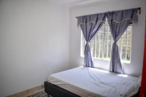 a bedroom with a bed and a window with blue curtains at Mella homes limuru in Limuru