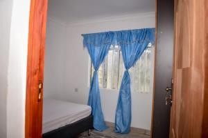 Mella homes limuru في Limuru: غرفة نوم وستارة زرقاء ونافذة