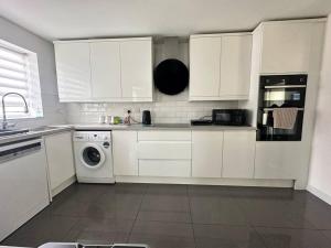 a kitchen with white cabinets and a washing machine at Sage House - Alton towers and Lake District in Stoke on Trent