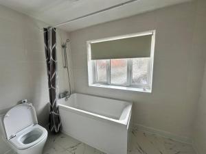 a bathroom with a tub and a toilet and a window at Sage House - City centre Hanley, Alton towers in Stoke on Trent