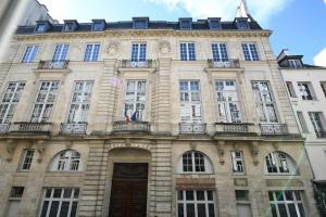un grand bâtiment en pierre avec des fenêtres et une porte dans l'établissement We Parisian The Marais Cozy Home, à Paris
