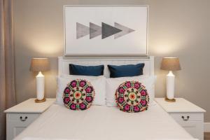a white bed with two lamps and two pillows on it at CAPE TOWN - MOUILLE POINT - SEA VIEW APARTMENT in Cape Town +18 photos