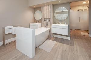 a bathroom with a tub and two sinks and a mirror at CAPE TOWN - MOUILLE POINT - SEA VIEW APARTMENT in Cape Town