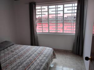 una camera da letto con un letto e una grande finestra di La Piedra Pintada de los Muiscas a Ibagué