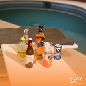 un grupo de botellas y vasos en una mesa junto a la piscina en Hotel Dali, en Reynosa