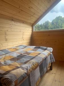 een bed in een houten kamer met een groot raam bij Vichnashi in Mestia