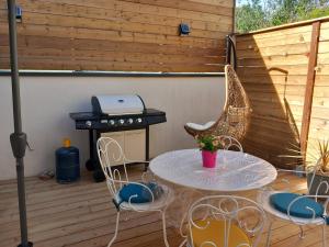 eine Terrasse mit einem Tisch, Stühlen und einem Grill in der Unterkunft Maison de charme L'hirondelle en Auvergne in Champs