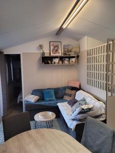 ein Wohnzimmer mit einem blauen Sofa und einem Tisch in der Unterkunft Mobilhome tout confort, proche Saint-Malo, à 50 m de la plage et du GR34 in Saint-Coulomb