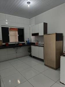 a large kitchen with a refrigerator and white tile floors at Home flat in Araguaína