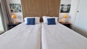 a bedroom with two white beds with blue pillows at Skyscraper apartment with panoramic views - floor 38 in Benidorm