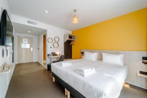 Beelodge Hotel Blois Centre في بلوا: غرفة نوم بسرير ابيض كبير وبجدار اصفر