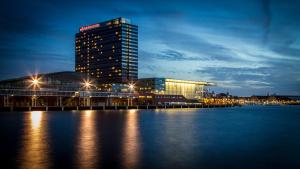 un grand bâtiment à côté de l'eau la nuit dans l'établissement Mövenpick Hotel Amsterdam City Centre, à Amsterdam
