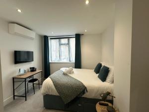 a bedroom with a bed and a desk and a window at Kings Gate House DH ApartHotels in Peterborough
