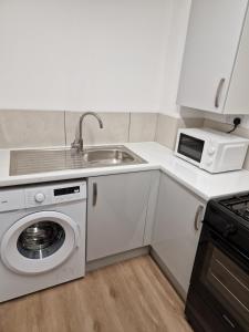 een keuken met een wastafel en een wasmachine bij CKB Flat- comfort, cosy, and secure! in Codsall