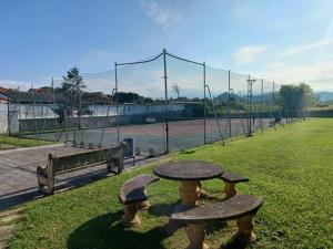 a picnic table and bench in a tennis court at Casa grande con jardín in Santa Cruz de Bezana