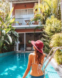 a woman in a hat sitting next to a swimming pool at Angam Suites Colombo in Sri Jayewardenepura Kotte