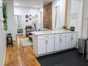 ニューヨークにあるLavish Downtown Manhattan Oasis in Union Squareの白いキャビネットとレンガの壁が備わるキッチン