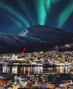 a city with a mountain and northern lights in the sky at Cozy apartment in Tromsø / Tromsdalen in Tromsø