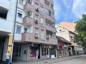 um edifício cor-de-rosa ao lado de uma rua em Small flat in the city heart em Novi Sad