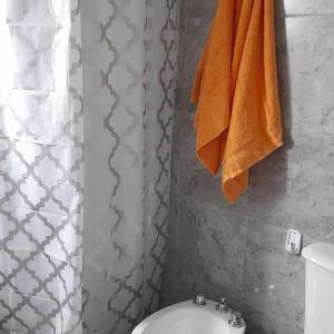 un baño con una toalla naranja colgada de una cortina de ducha. en Cabañas tu despertar en Oro Verde