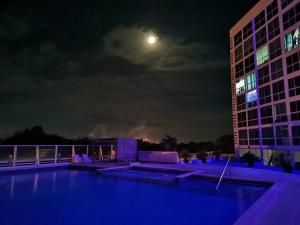 una vista de un edificio por la noche con la luna en Apartamento de playa con vista al mar en coronado en Playa Coronado