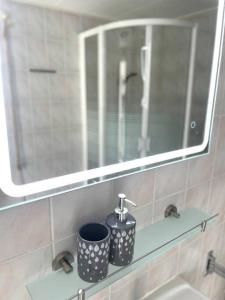 a mirror and two cups on a shelf in a bathroom at Beach Bungalow - Noordwijk aan Zee in Noordwijkerhout