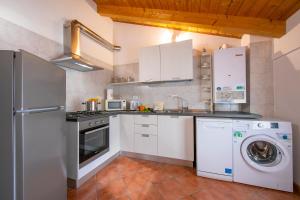 a kitchen with white cabinets and a washer and dryer at Residenza al Ponte in Arco